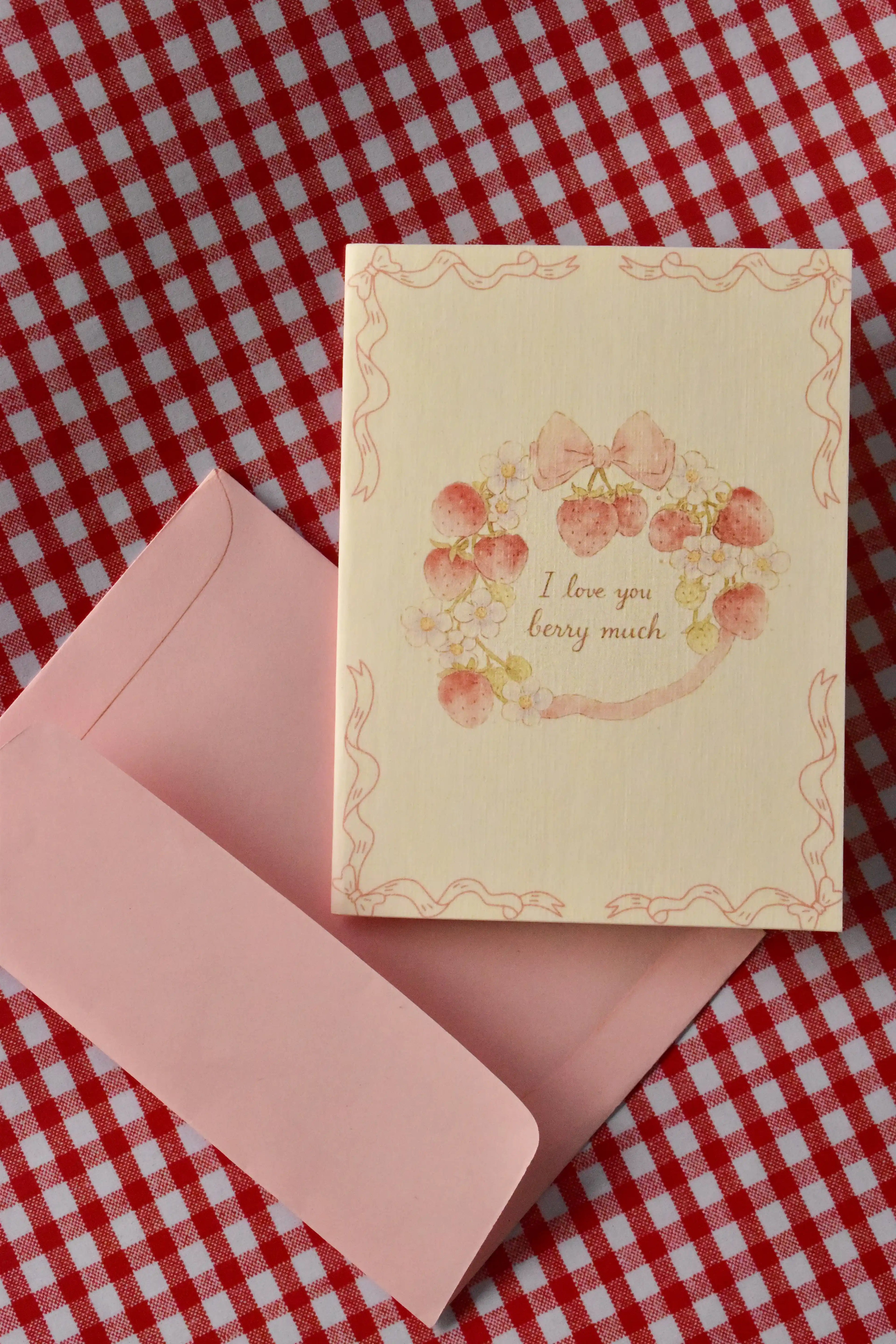 This image showcases the front of the Love You Berry Much card, highlighting the sweet strawberry wreath, bow, and flower motif and the soft, warm cream colour of the card, ready to share a heartfelt message.