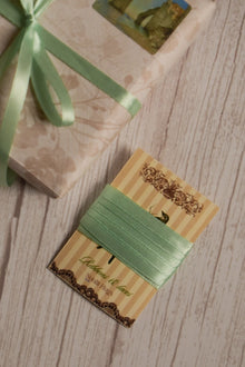 Mint Breeze Ribbon shown on a Sunlit Hugs ribbon card beside a wrapped gift, highlighting its soft mint green shade for packaging, crafts, and bows.
