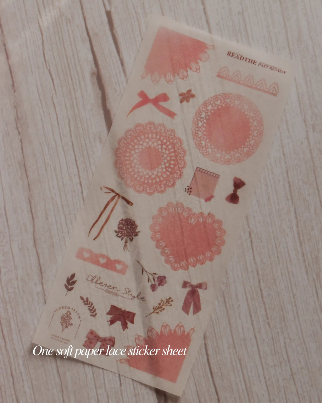 Decorative paper lace sticker sheet with floral and bow designs on a wooden surface.
