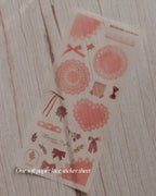 Decorative paper lace sticker sheet with floral and bow designs on a wooden surface.
