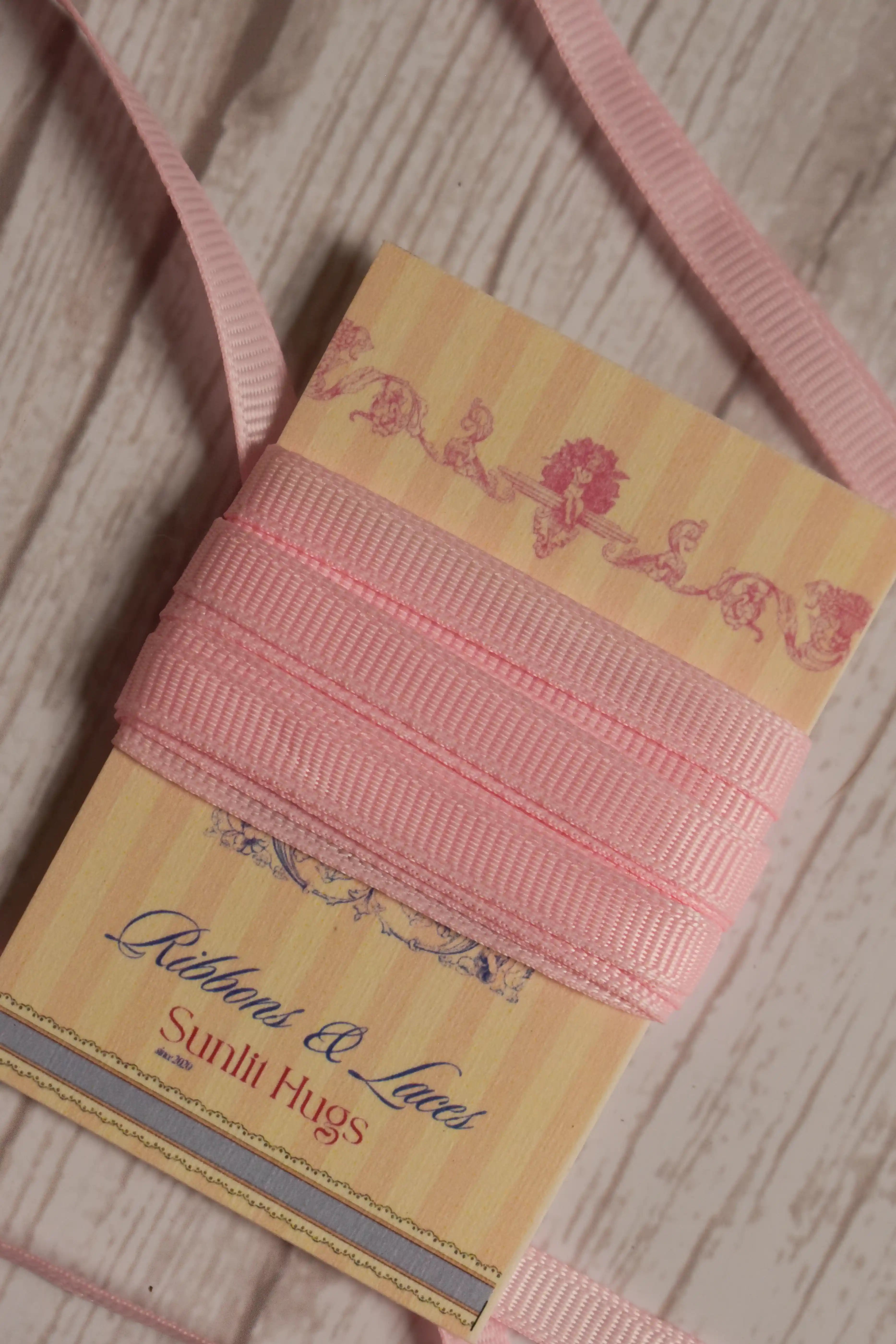 Petal Silk Ribbon wrapped around a printed Sunlit Hugs ribbon card, showing its blush pink tone for crafts, packaging, bows, and gift styling.
