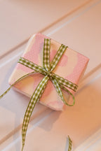 This image shows a beautifully wrapped gift box, featuring the Pine Picnic ribbon tied into a sweet bow. The ribbon's elegant green and white pattern adds a fresh and charming touch to the present.