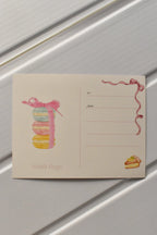 This image focuses on the reverse of the postcard, highlighting the beautiful macaron stack illustration that adds a final touch of sweetness before the postcard is sent.