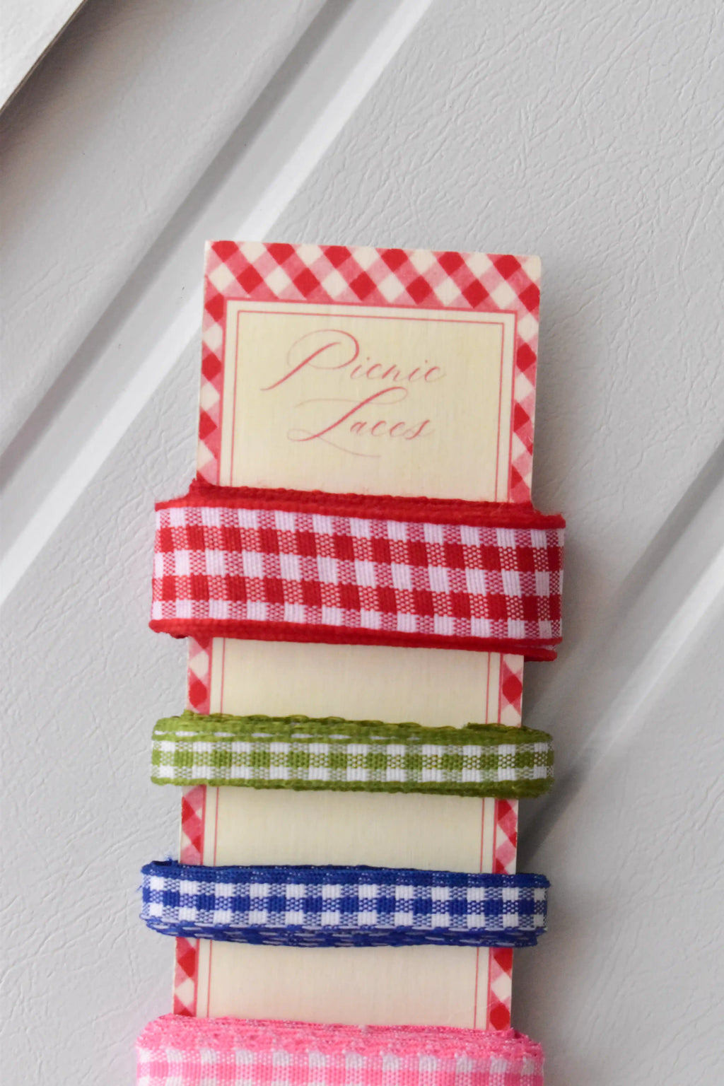Four narrow gingham ribbons in red, green, blue, and pink, highlighting the textured weave on the 'Picnic Laces' card.