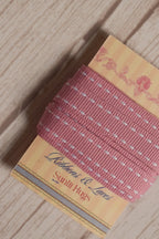 Rosette Stitches Ribbon wrapped around a printed Sunlit Hugs ribbon card, showing its 10 mm width, pink shade, and stitched decorative design.