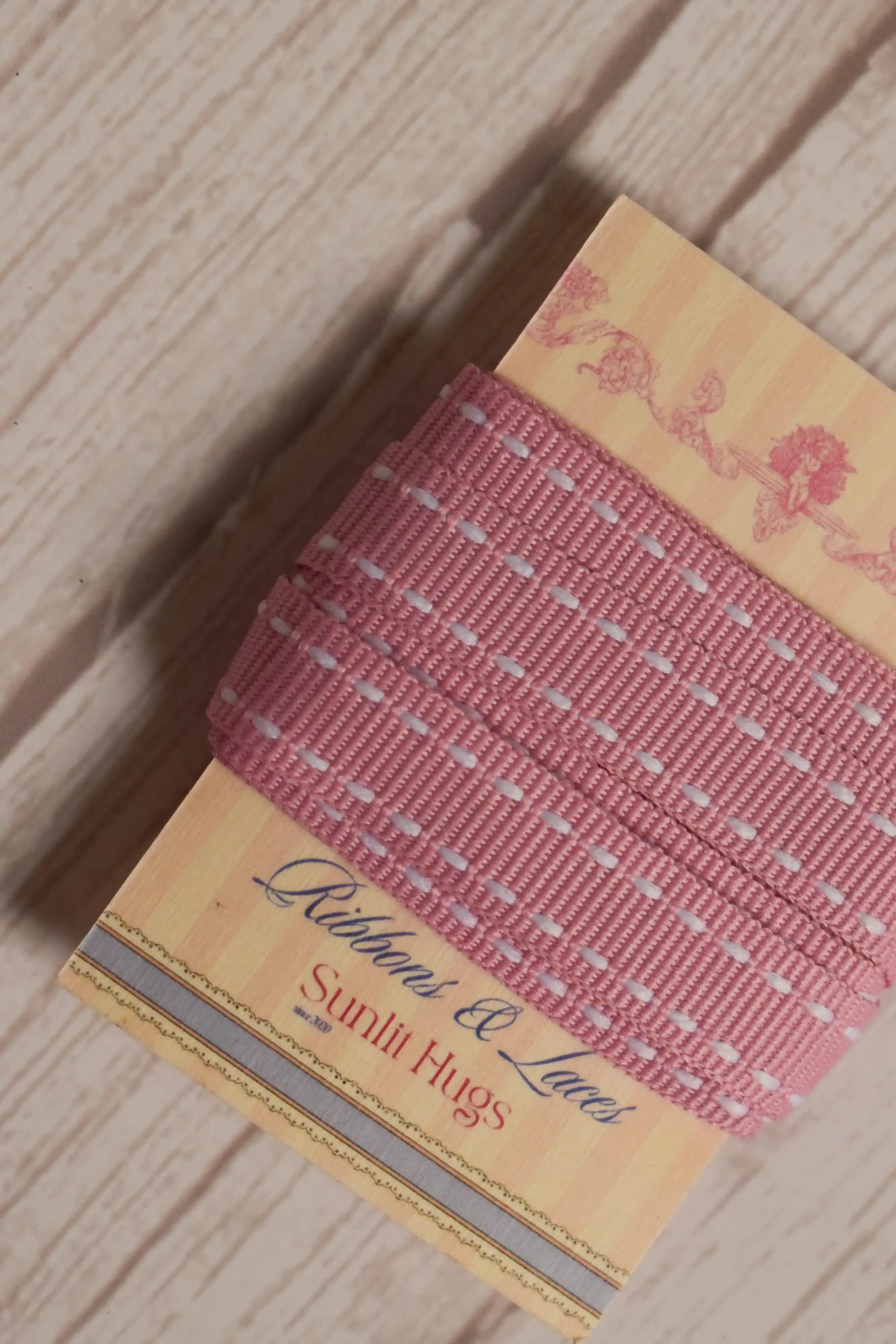 Rosette Stitches Ribbon wrapped around a printed Sunlit Hugs ribbon card, showing its 10 mm width, pink shade, and stitched decorative design.