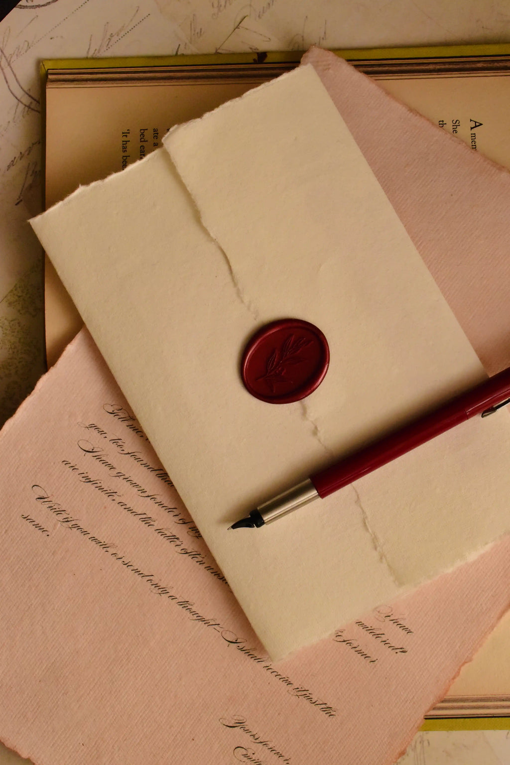 This warm, staged shot highlights the final, dramatic presentation: the scarlet wax seal securing the handmade ivory envelope, symbolizing a timeless and private act of old-world letter writing.