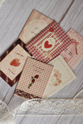 Flat lay of the Sunlit Hugs Set of 6 Love Series Cards featuring vintage romantic designs like strawberries, red plaid, pink gingham, and floral lace, arranged on a white wooden table with decorative lace.