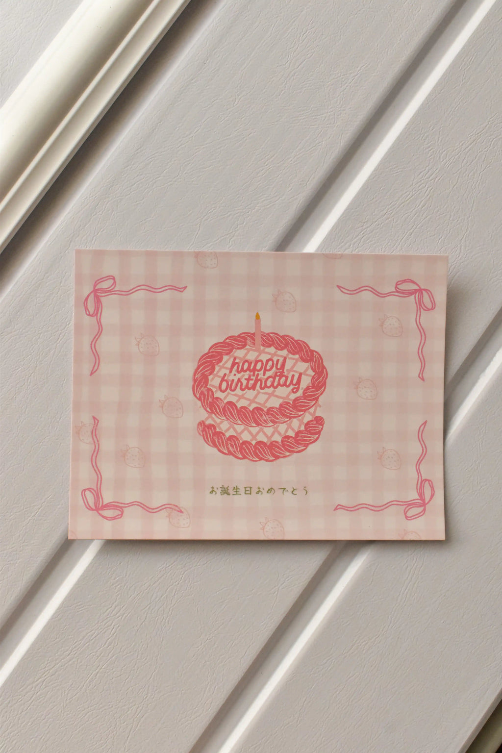 A detailed view of the postcard's front, showcasing the cute pink cake illustration and the soft pink gingham pattern that gives it a sweet, nostalgic charm.