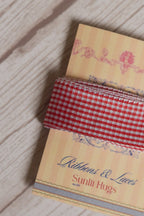 Close-up of Strawberry Jam Ribbon displayed on a Sunlit Hugs ribbon card, highlighting its strawberry red and white checked pattern.