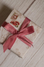 A vintage-style gift parcel tied with Strawberry Jam Ribbon, showing the red and white checked ribbon styled as a bright decorative bow.