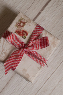 A vintage-style gift parcel tied with Strawberry Jam Ribbon, showing the red and white checked ribbon styled as a bright decorative bow.