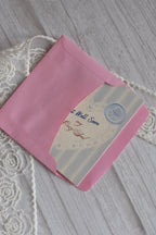 Sunlit Hugs Get Well Soon Cozy Soul Greeting Card partially inside a pink envelope on a white wooden surface.