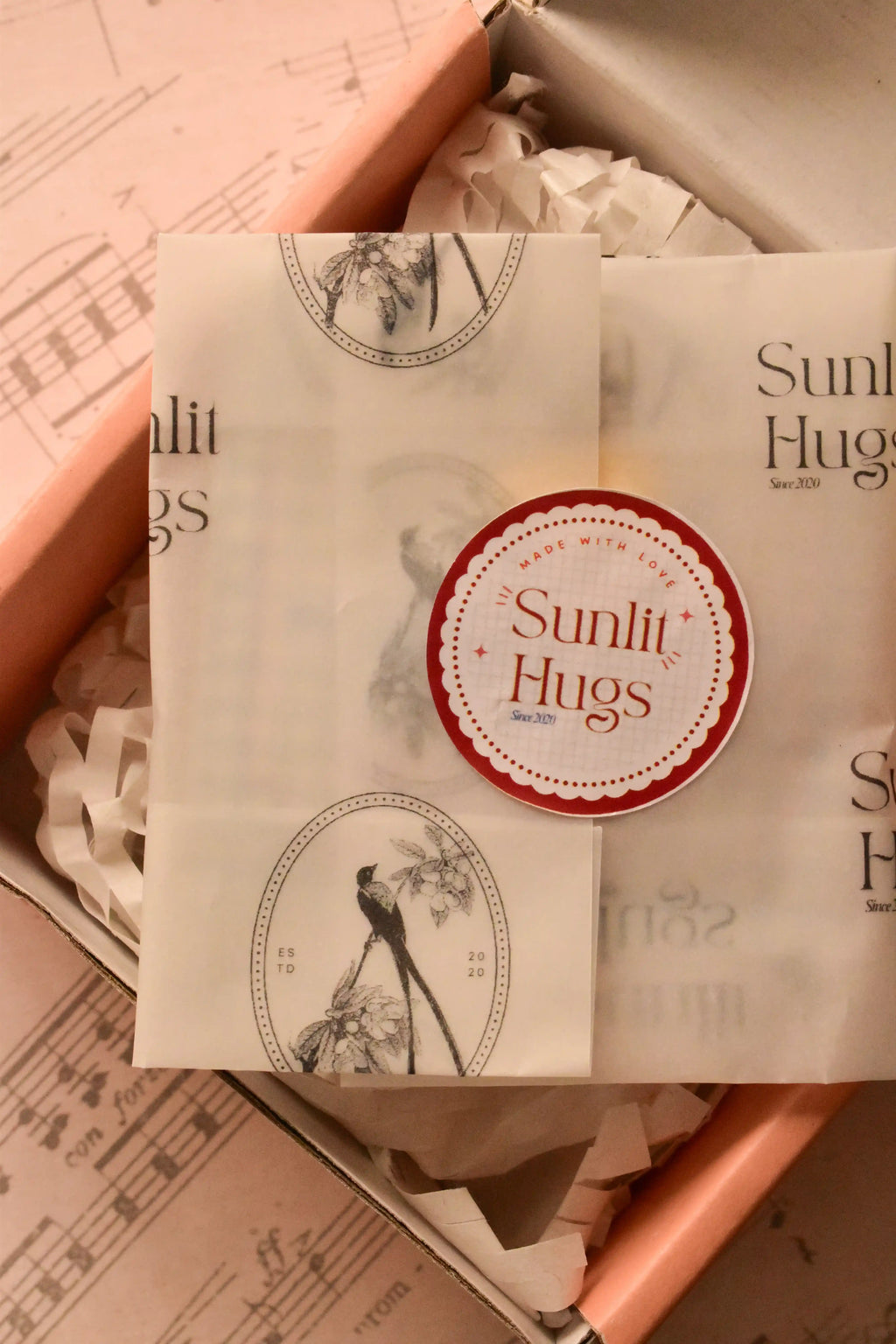 This image shows the beautiful presentation of the locket gift, wrapped in Sunlit Hugs tissue paper and sealed with a sticker, assuring customers of a warm, high-quality gift experience.