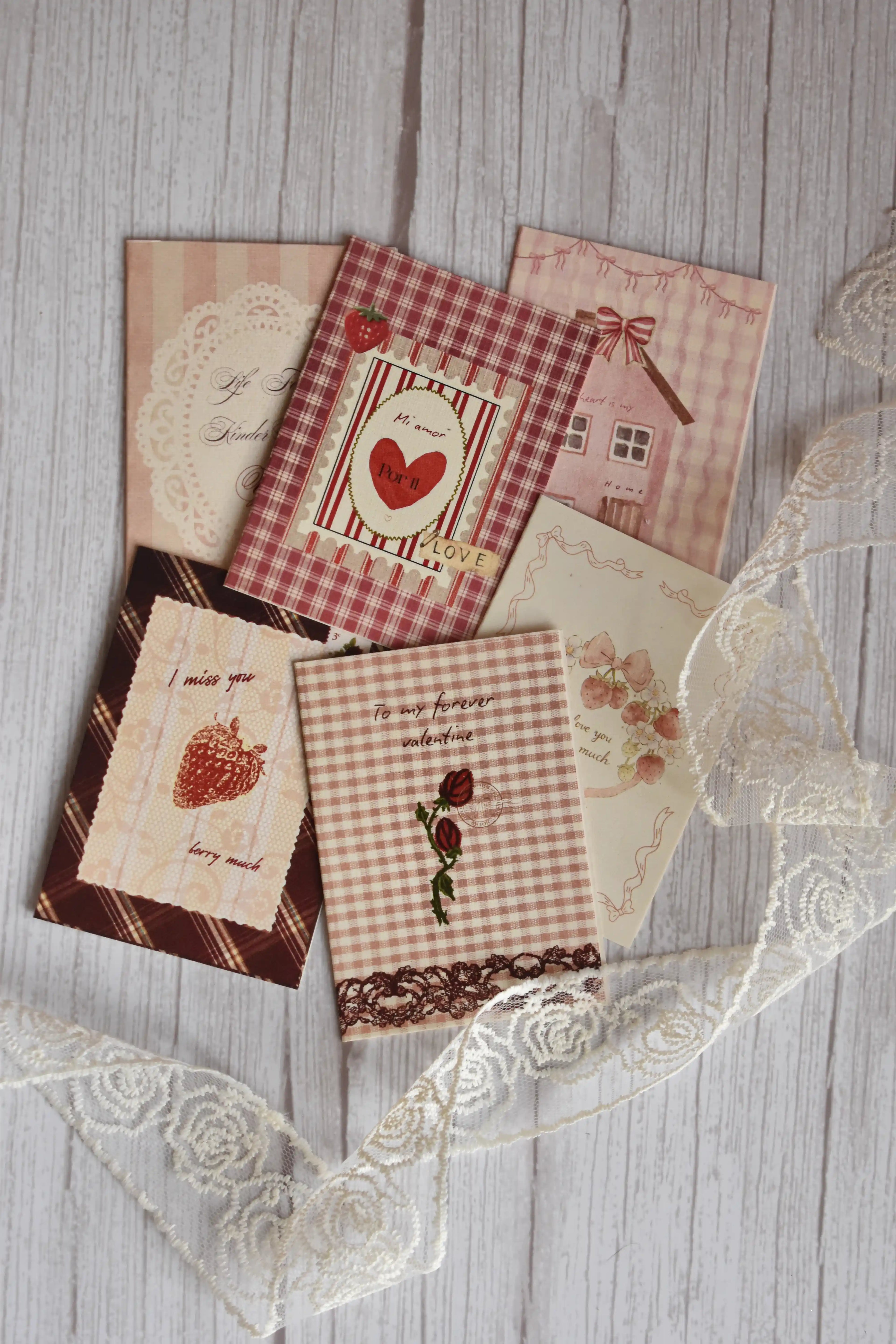 Angled view of the Sunlit Hugs Set of 6 Love Series Cards bundle showcasing various romantic greetings including "To my forever valentine" and "I miss you berry much" alongside delicate white floral lace.