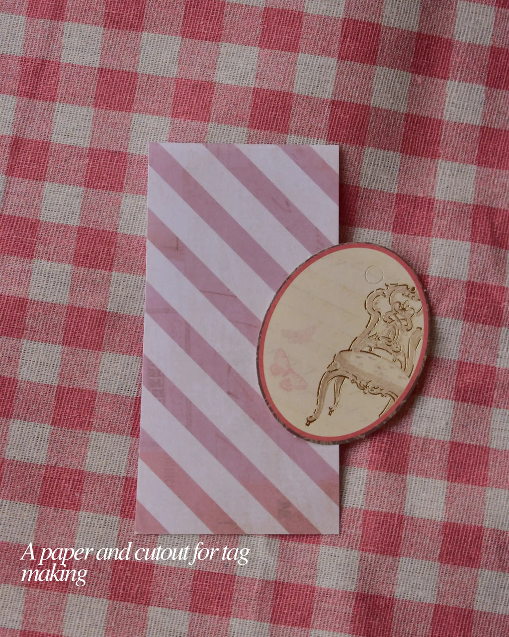 Pink striped paper with a wooden chair cutout resting on it, for tag making in the journaling kit.