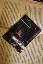 Flat lay of the 'The Sacred Window' Landour Photo Print tucked inside a vintage book, featuring fine art mountain photography of a monochrome Himalayan window and delicate floral details.