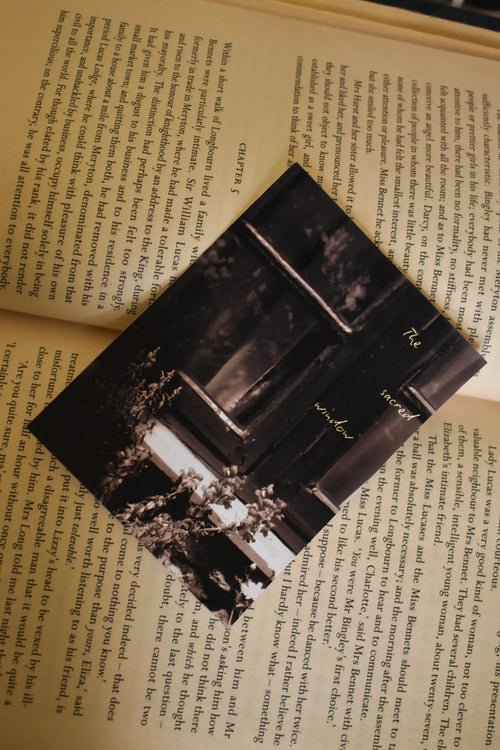 Flat lay of the 'The Sacred Window' Landour Photo Print tucked inside a vintage book, featuring fine art mountain photography of a monochrome Himalayan window and delicate floral details.