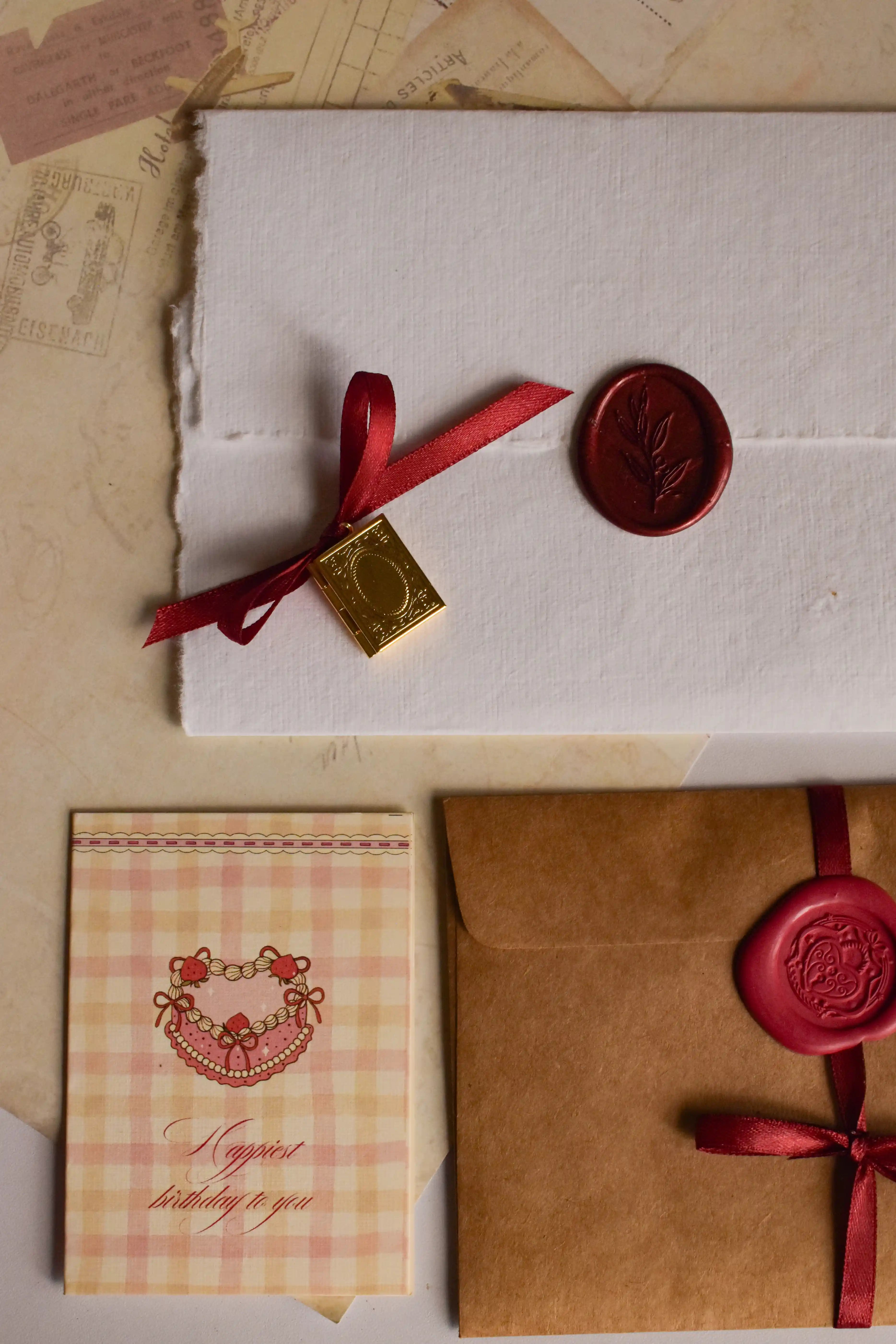 A romantic birthday gift bundle featuring a Classic Scarlet Vintage Letter, personalised Golden Book Pendant, birthday card, and handcrafted keepsakes.