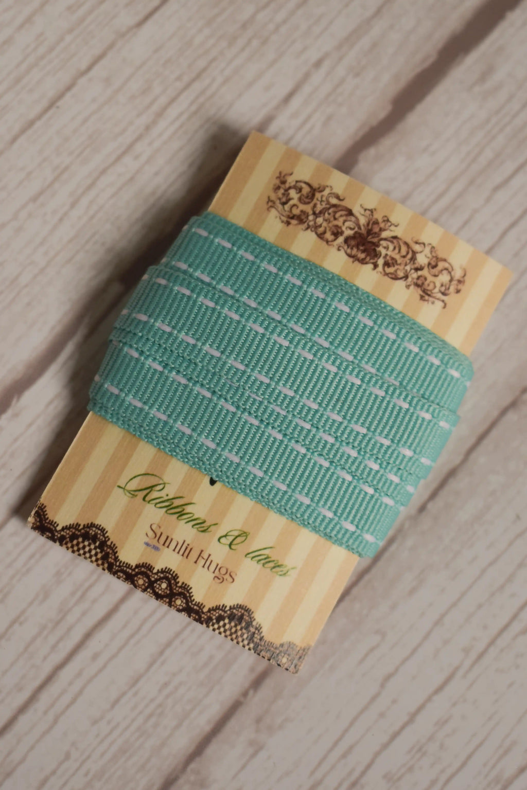 Turquoise stitches Ribbon displayed on a Sunlit Hugs card against a light wooden background, highlighting the 10 mm stitched ribbon style.