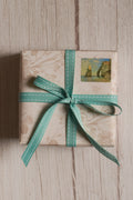 A gift box wrapped with Turquoise stitches Ribbon in a neat bow, showing how the stitched turquoise ribbon can be used for pretty gift wrapping and parcel styling.