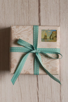 A gift box wrapped with Turquoise stitches Ribbon in a neat bow, showing how the stitched turquoise ribbon can be used for pretty gift wrapping and parcel styling.