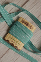 Turquoise stitches Ribbon arranged loosely around the display card, showing its length, stitched pattern, and suitability for gift wrapping, crafts, and decorative packaging.