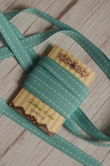 Turquoise stitches Ribbon arranged loosely around the display card, showing its length, stitched pattern, and suitability for gift wrapping, crafts, and decorative packaging.