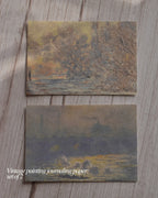 Two pieces of vintage painting journaling paper on a wooden surface.