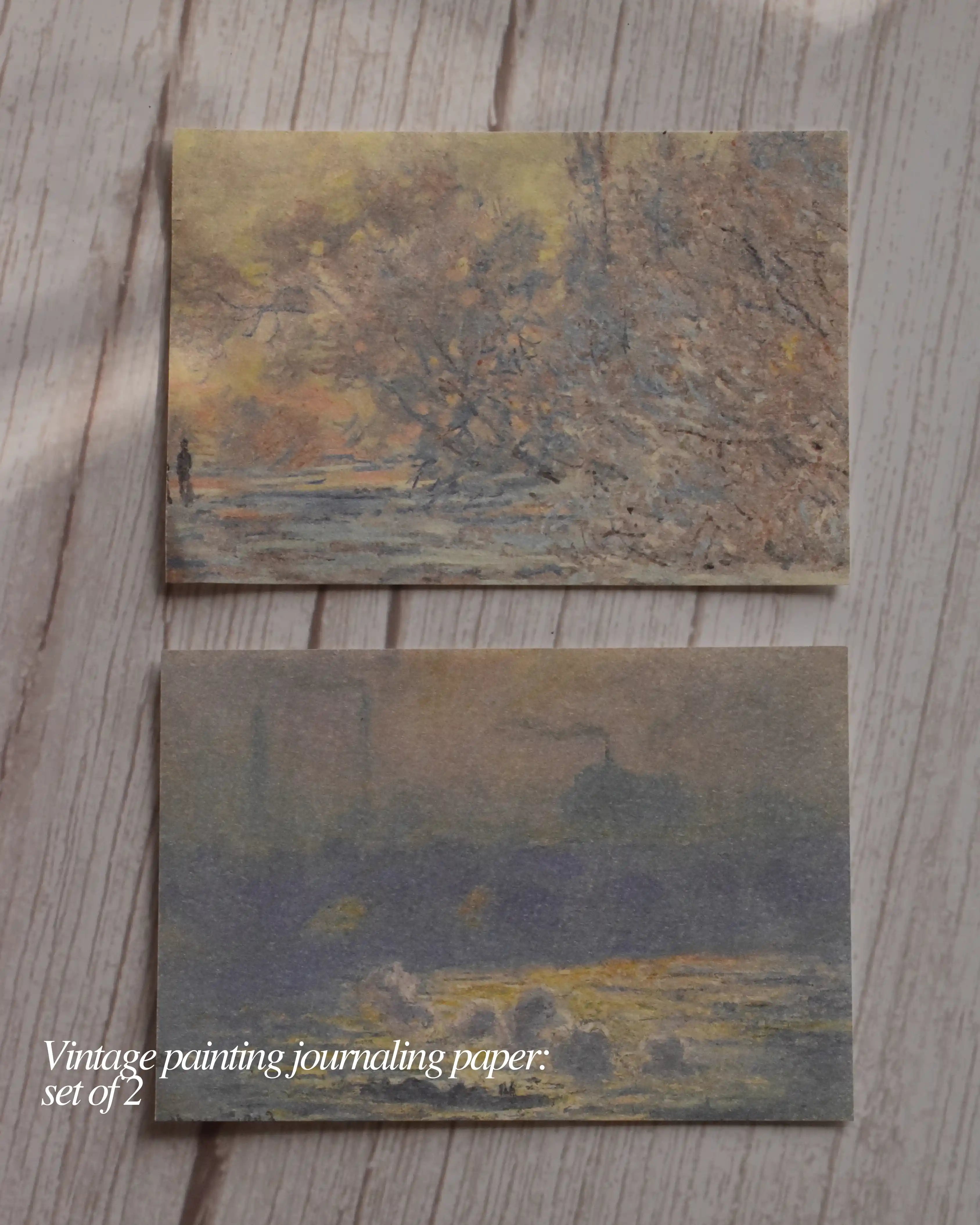 Two pieces of vintage painting journaling paper on a wooden surface.