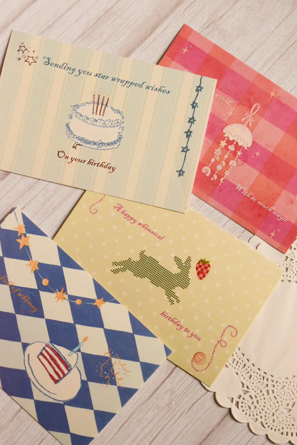 Four 4 x 6 inch birthday postcards displayed together, featuring a birthday cake with star-wrapped wishes, a blue checkered cake design, a rabbit with a strawberry and a magical jellyfish illustration.
