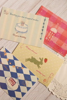 Four 4 x 6 inch birthday postcards displayed together, featuring a birthday cake with star-wrapped wishes, a blue checkered cake design, a rabbit with a strawberry and a magical jellyfish illustration.