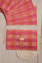 A single magical jellyfish postcard displayed below a collection of matching postcards, featuring warm pink and coral checks, tiny stars and a heartfelt message.