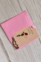 A vintage gingham mini Valentine card with roses is styled on a warm wooden surface.