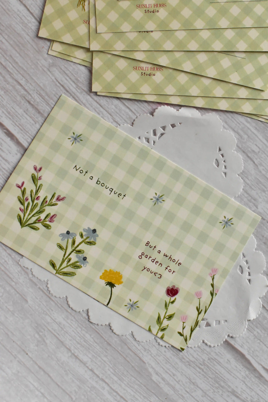 A cottagecore green gingham garden postcard is shown with flower illustrations.