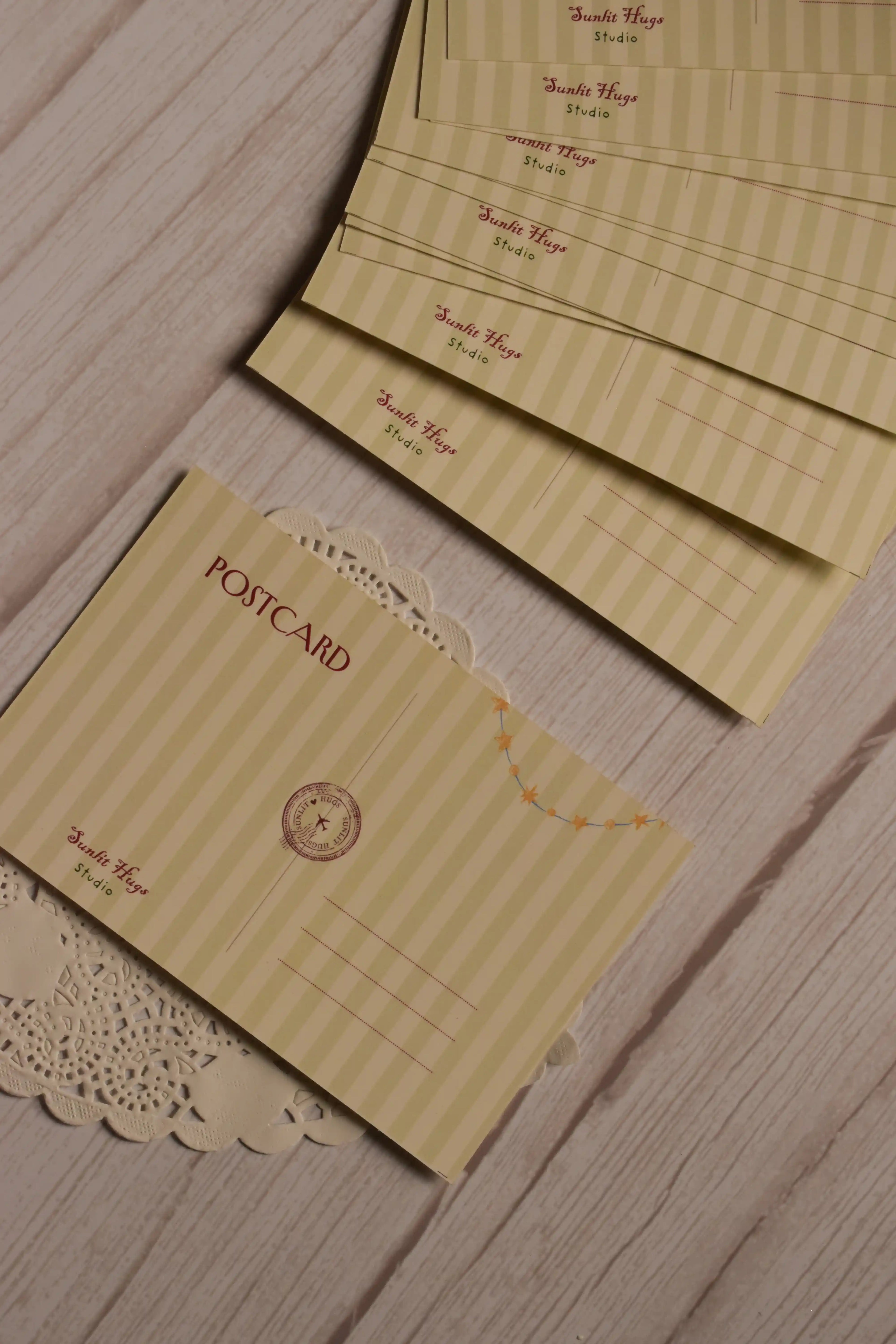 Back design of the birthday postcard displayed with several matching postcard backs, showing the writing area, Sunlit Hugs Studio branding and yellow star garland detail.