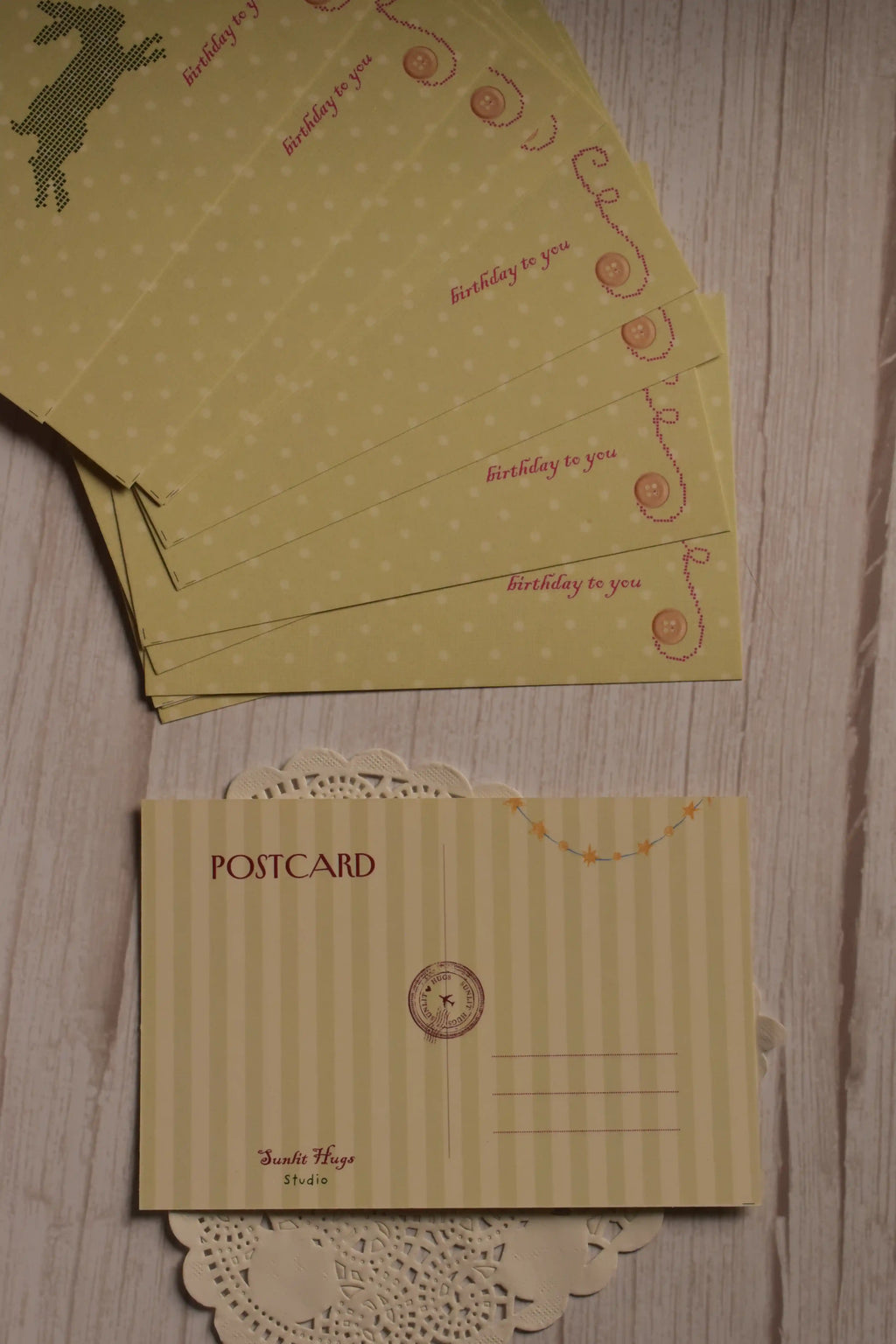 The cream striped back of the birthday postcard displayed alongside multiple yellow rabbit and strawberry postcard fronts.