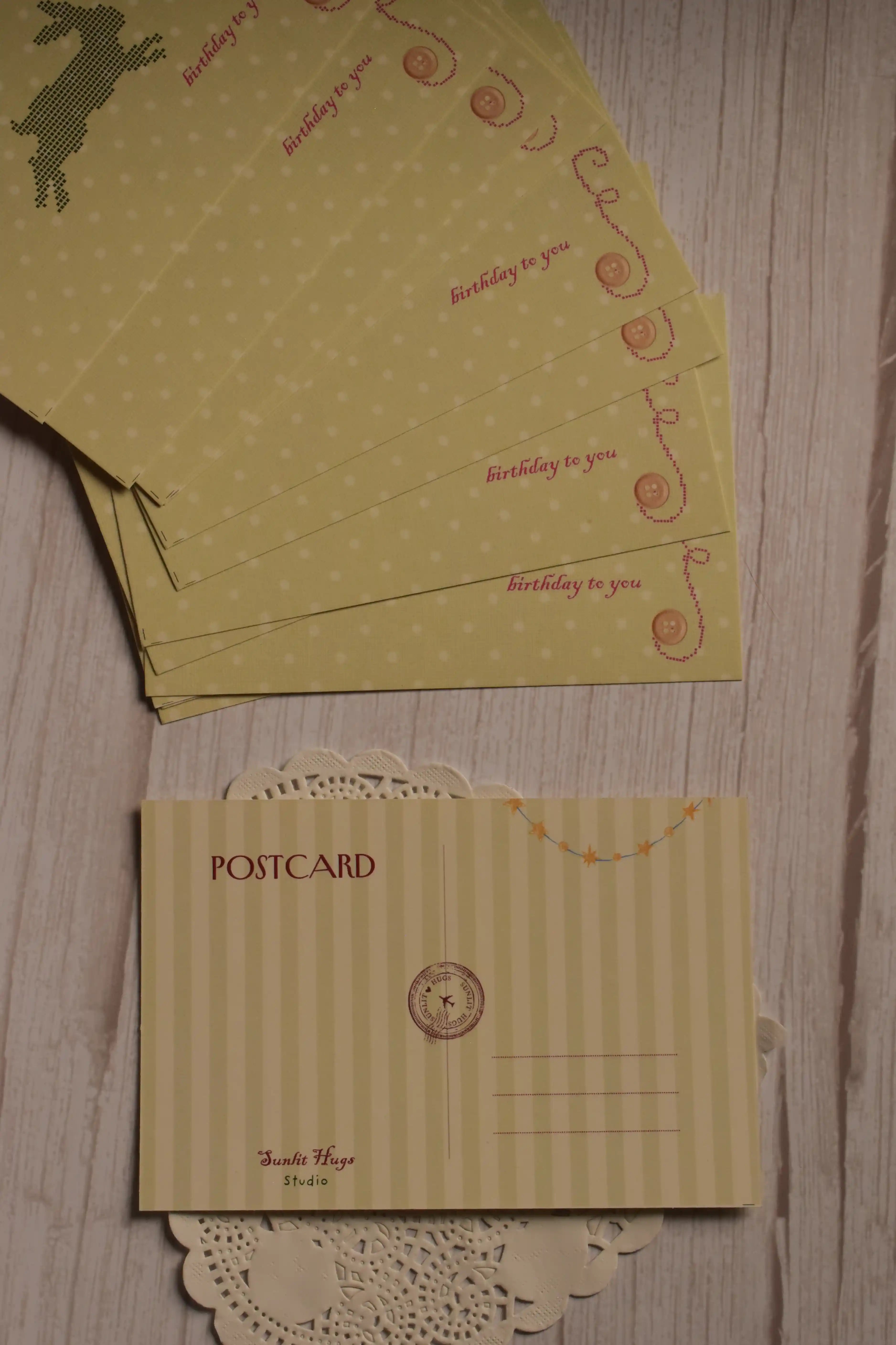 The cream striped back of the birthday postcard displayed alongside multiple yellow rabbit and strawberry postcard fronts.
