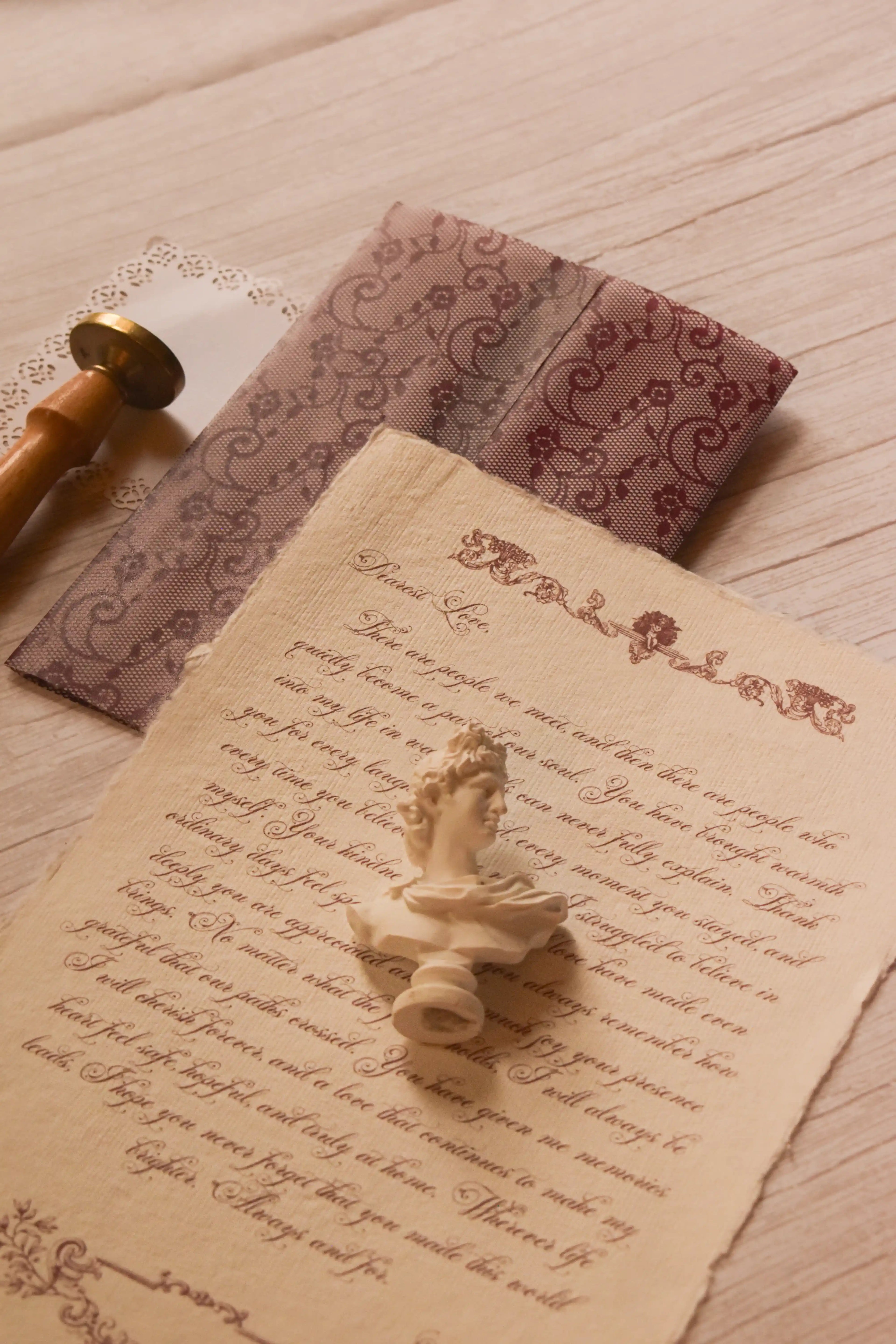 Rosie personalised vintage letter styled on textured handmade paper beside its deep burgundy lace-patterned vellum wrapper and vintage stationery details.