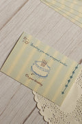 Close-up view highlighting the illustrated birthday cake, celestial stars, soft striped background and the message “Sending you star wrapped wishes on your birthday.”