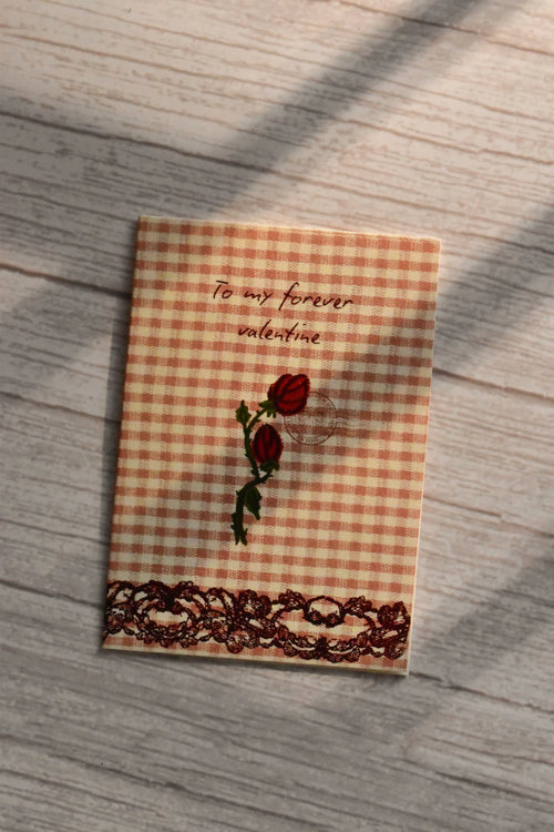 A peach gingham mini card reads To my forever valentine above red roses and a brown lace border.