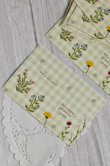 A green gingham garden postcard reads Not a bouquet, but a whole garden for you with colorful flowers.