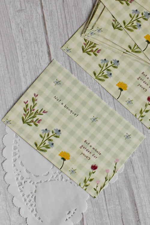 A green gingham garden postcard reads Not a bouquet, but a whole garden for you with colorful flowers.