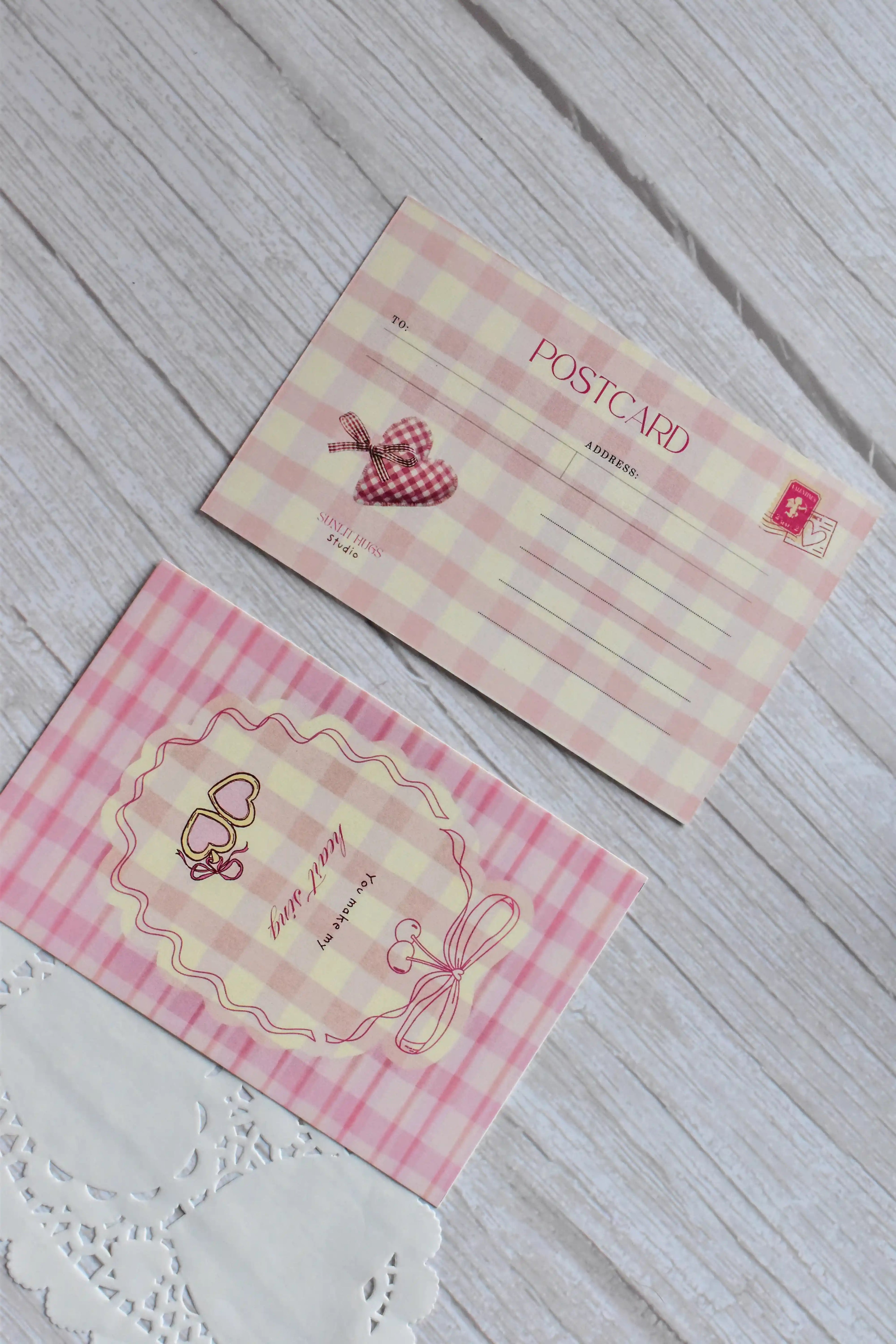 A pink gingham postcard reads You Make My Heart Sing with retro cherries and bow illustrations.