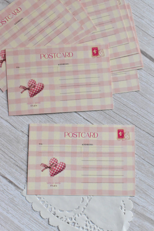 A pink gingham postcard with cherries and bows reads You make my heart sing.